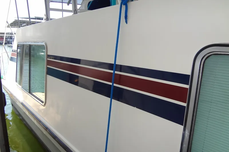 Slide: The Image of 1995 Harbor Master 52 boat with blue and red stripes docked at marina. - 12