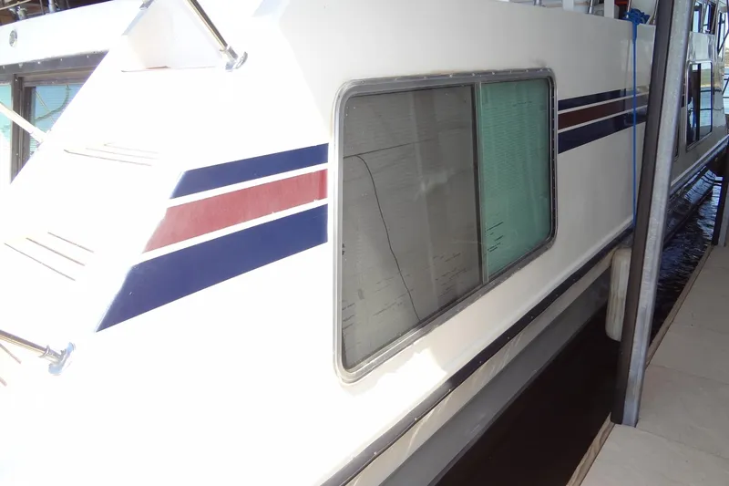 Slide: The Image of 1995 Harbor Master 52 houseboat with striped exterior docked at marina. - 13