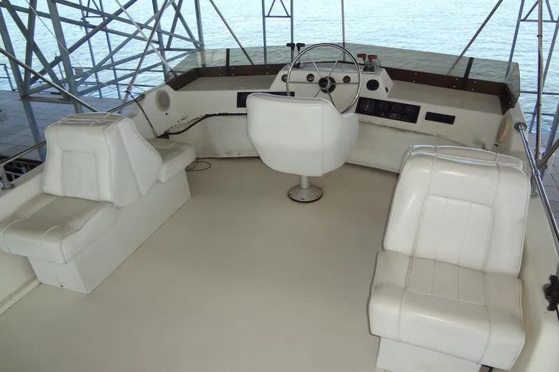Slide: The Image of 1995 Harbor Master 52 boat helm with white seating and steering wheel, docked by water. - 18