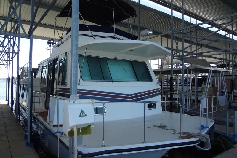 Slide: The Image of 1995 Harbor Master 52 houseboat docked under a covered marina. - 3