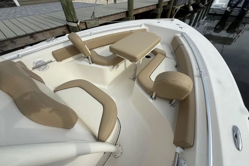 Slide: The Image of 2018 Key West 219 FS boat interior with beige seating and table, docked by wooden pier. - 10