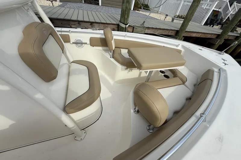 Slide: The Image of 2018 Key West 219 FS boat interior with tan seating and table, docked by wooden pier. - 11