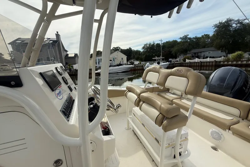 Slide: The Image of 2018 Key West 219 FS boat interior with beige seating and control panel, docked by waterfront homes. - 16