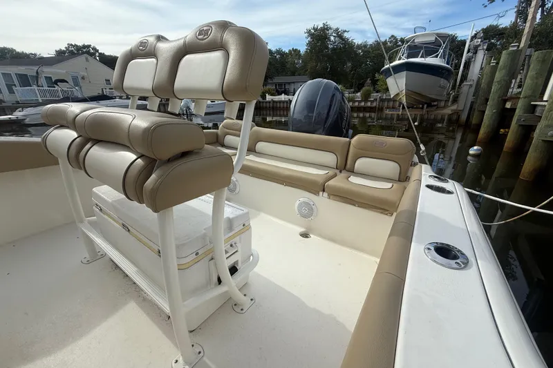 Slide: The Image of 2018 Key West 219 FS boat interior with tan seating and console, docked near waterfront homes. - 17