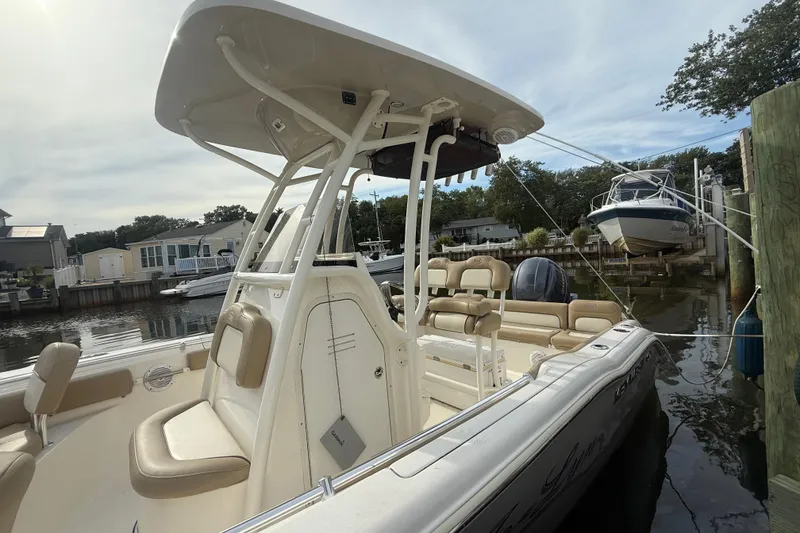 Slide: The Image of 2018 Key West 219 FS boat docked in a marina, featuring beige seating and a T-top. - 26