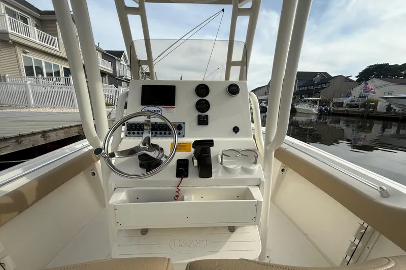 Slide: The Image of 2018 Key West 219 FS boat console with steering wheel and controls, dockside view. - 42