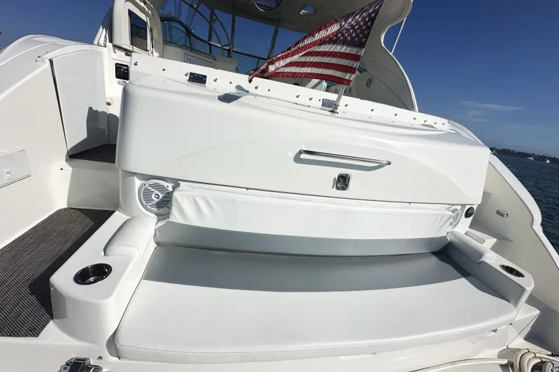 Slide: The Image of 2007 Cruisers Yachts 540 Express deck with seating and American flag, under clear blue sky. - 11