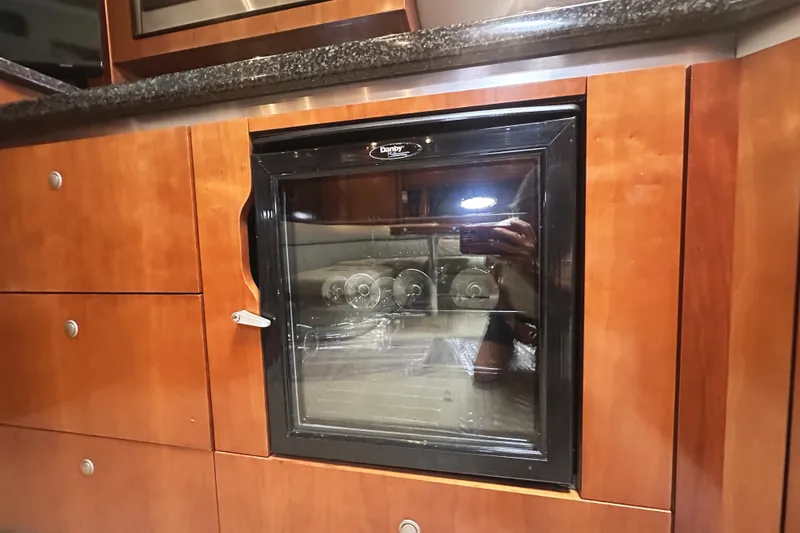 Slide: The Image of 2007 Cruisers Yachts 540 Express interior with built-in mini fridge and wooden cabinetry. - 29