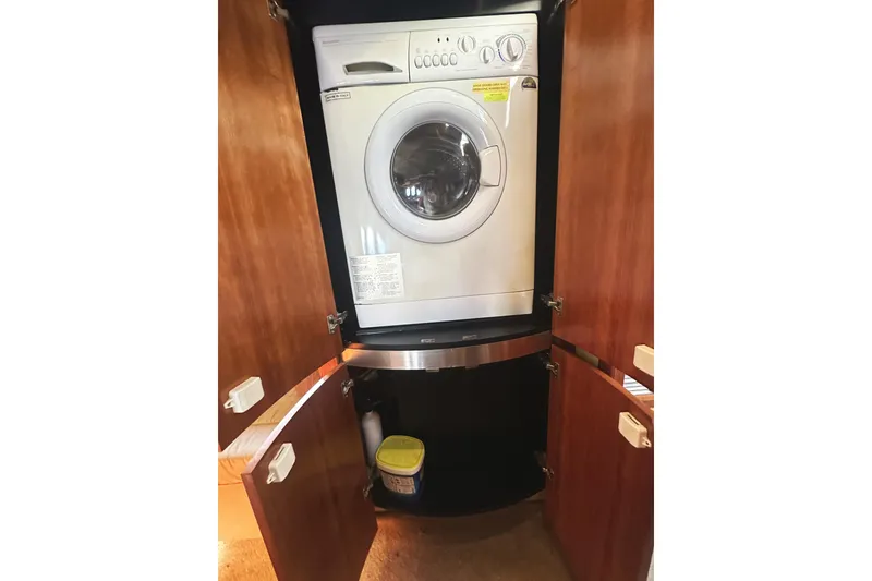 Slide: The Image of 2007 Cruisers Yachts 540 Express laundry area with washing machine in wooden cabinet. - 46
