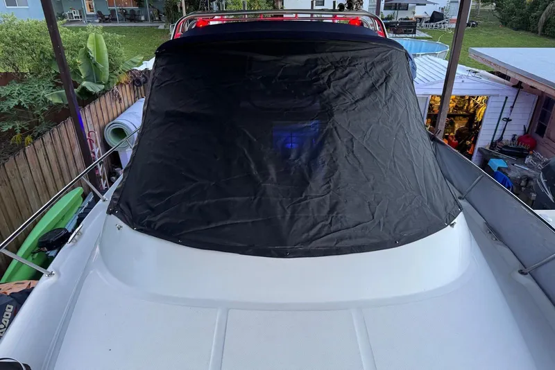 Slide: The Image of 2006 Sea Ray 290 Amberjack boat on trailer under canopy, surrounded by trees and equipment. - 24