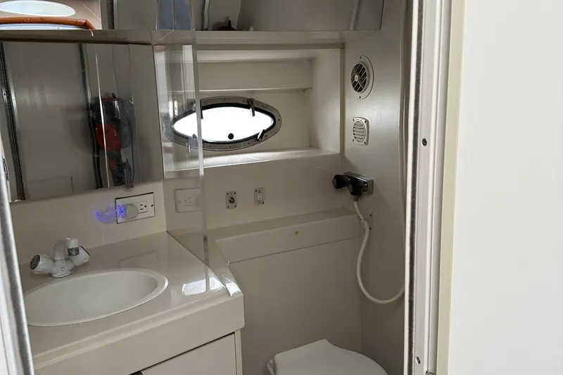 Slide: The Image of 1995 Carver 325 Aft Cabin bathroom with sink, mirror, and porthole window. - 16