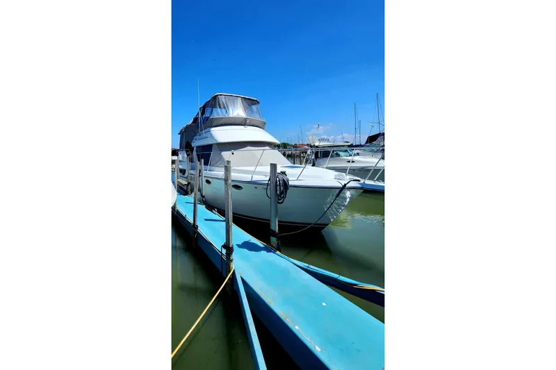Slide: The Image of 1995 Carver 325 Aft Cabin yacht docked at marina under clear blue sky. - 4