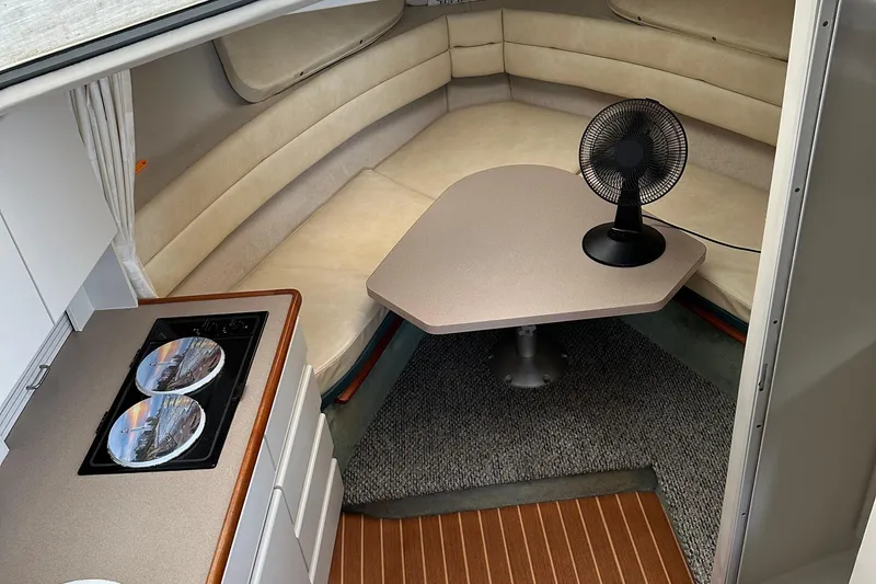 Slide: The Image of 1995 Carver 325 Aft Cabin interior with kitchenette, seating, and table fan. - 6