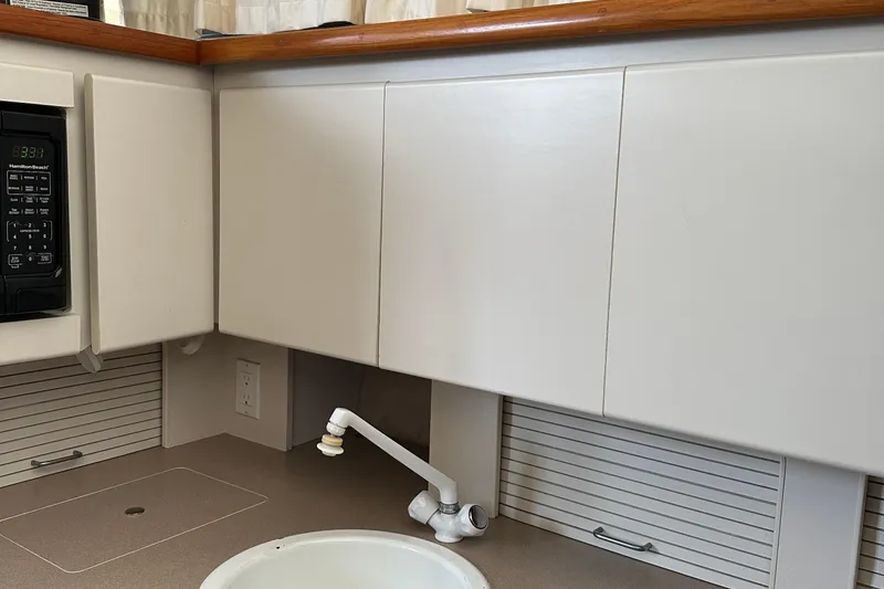Slide: The Image of 1995 Carver 325 Aft Cabin kitchen with cabinets, sink, and microwave. - 9