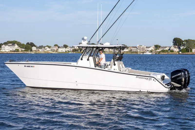 Slide: The Image of 2020 Freeman 34VH boat cruising on a calm lake with houses in the background. - 4