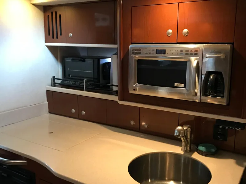 Slide: The Image of 2008 Sea Ray 330 Sundancer kitchen with microwave, sink, and wooden cabinetry. - 17