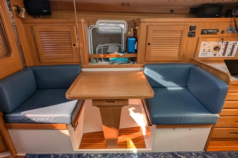 Slide: The Image of Interior of a 1995 Catalina 36 MkII sailboat with blue cushioned seating and wooden table. - 24