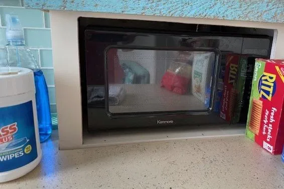 Slide: The Image of Kenmore microwave in a kitchen with cleaning supplies and snacks nearby. - 12