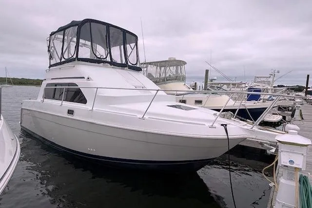 Slide: The Image of 1996 Mainship 31 Sedan Bridge boat docked at marina under cloudy sky. - 2