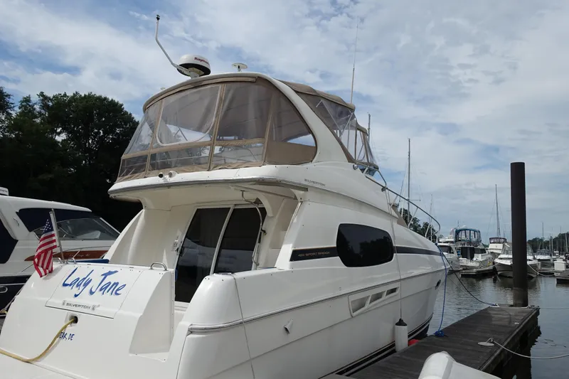 The Image of 2001 Silverton 410 Sport Bridge yacht docked at marina under cloudy sky. - 0