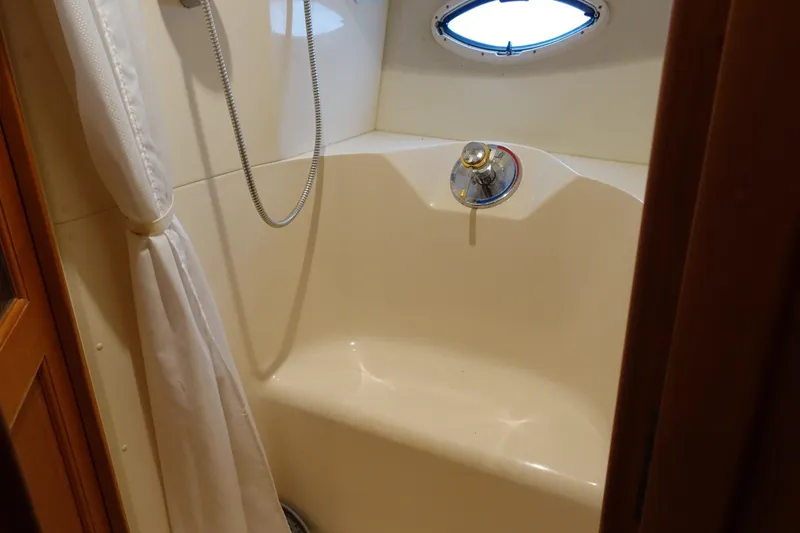 Slide: The Image of Shower area inside 2001 Silverton 410 Sport Bridge yacht, featuring curtain and porthole. - 22