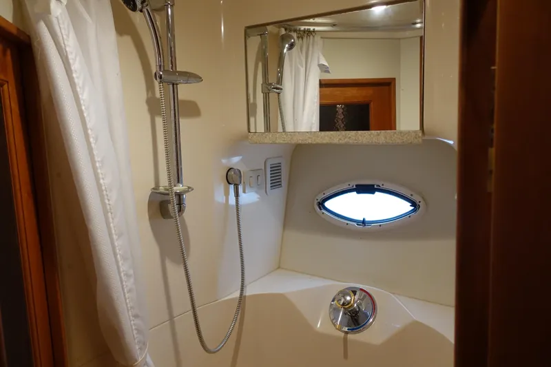 Slide: The Image of Bathroom interior of 2001 Silverton 410 Sport Bridge yacht, featuring shower and porthole window. - 23