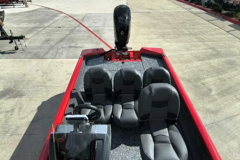 Slide: The Image of 2026 Tracker Pro Team 175 Crappie Edition boat with four seats and a motor, parked on concrete. - 6