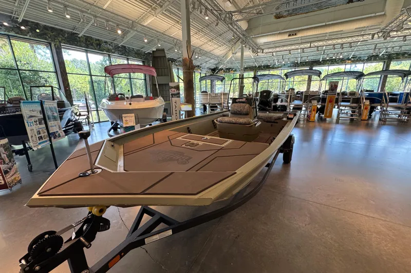 Slide: The Image of 2026 Tracker Grizzly 1860 CC boat displayed in a showroom with other boats. - 2