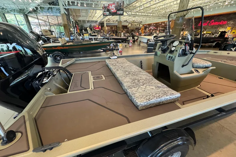 Slide: The Image of 2026 Tracker Grizzly 1860 CC boat interior with seating and control console in showroom. - 3