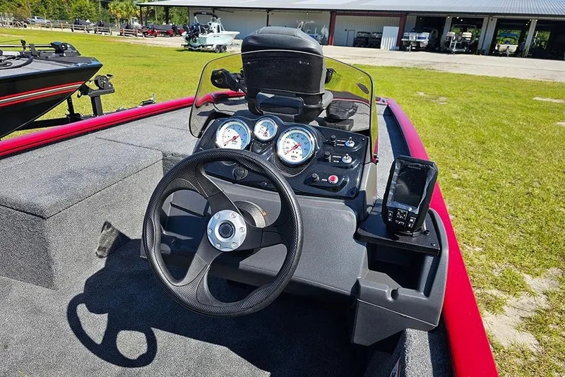 Slide: The Image of 2026 Tracker Pro 170 boat dashboard with steering wheel and gauges, parked on grass. - 15