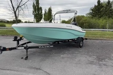 The Image of 2026 Tahoe T16 boat on trailer, parked outdoors, showcasing sleek design and mint green hull. - 0
