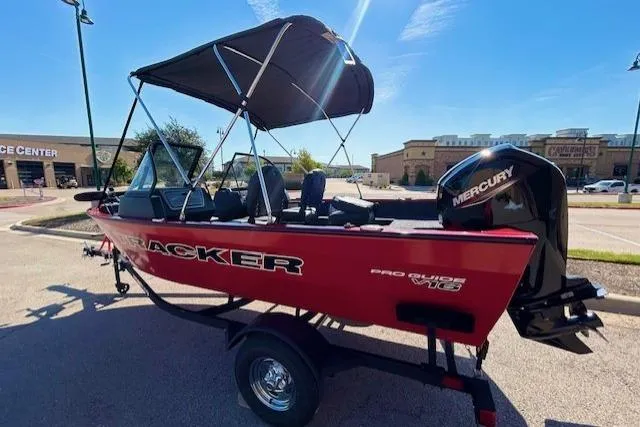 Slide: The Image of 2026 Tracker Pro Guide V-16 WT boat with Mercury engine, parked outdoors under blue sky. - 2