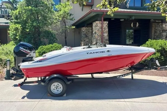 The Image of 2026 Tahoe T16 boat in red and white on a trailer, parked outdoors. - 58