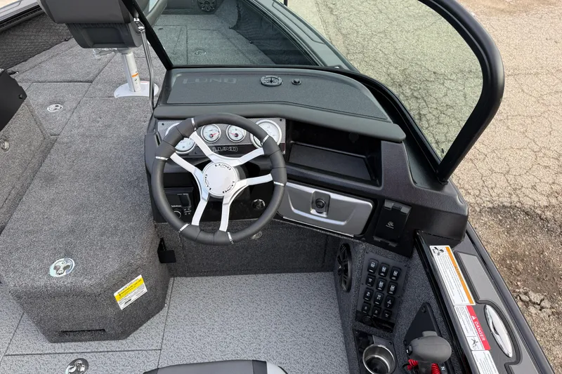 Slide: The Image of Interior of 2026 Lund 1975 Pro-V Sport boat, featuring steering wheel and dashboard controls. - 23