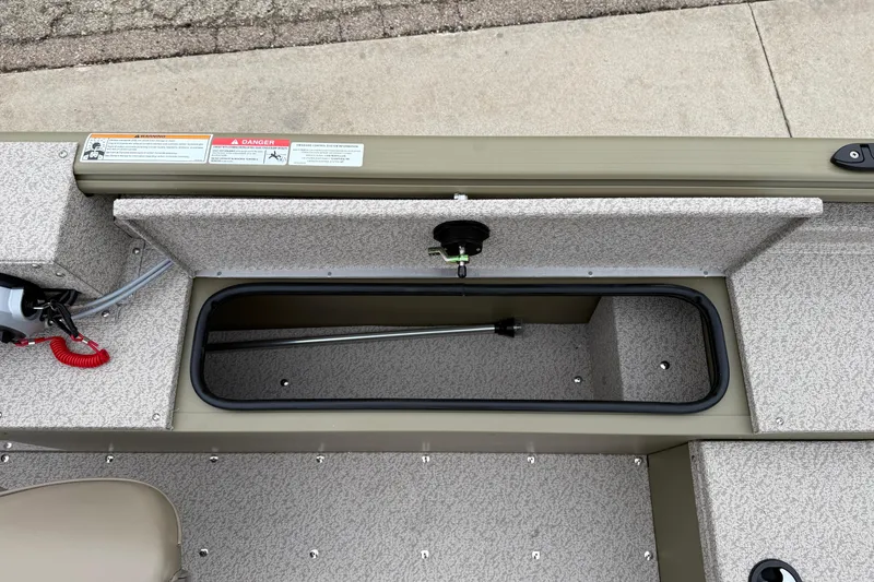 Slide: The Image of 2026 Lund 1675 Alaskan SS boat interior storage compartment with safety labels. - 22