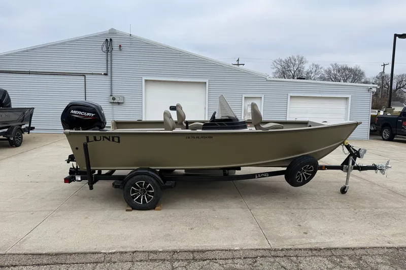 Slide: The Image of 2026 Lund 1675 Alaskan SS boat on trailer, parked outside a building. - 4