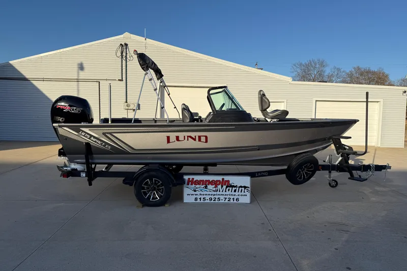 The Image of 2026 Lund 1875 Impact XS Sport boat on trailer, displayed at Hennepin Marine dealership. - 0