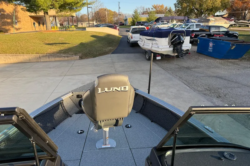 Slide: The Image of 2026 Lund 1875 Impact XS Sport boat parked, featuring a comfortable seat and spacious deck. - 13