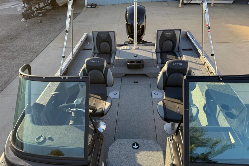 Slide: The Image of 2026 Lund 1875 Impact XS Sport boat interior with seating and windshield, docked outdoors. - 17