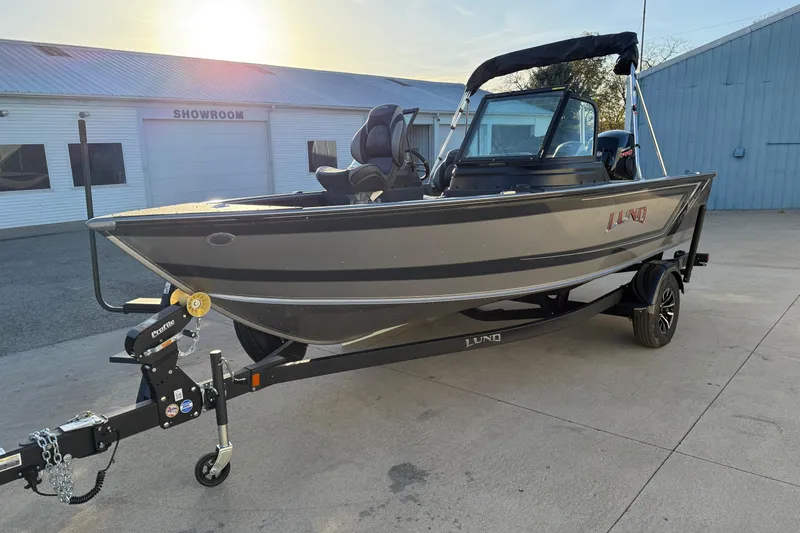 Slide: The Image of 2026 Lund 1875 Impact XS Sport boat on trailer outside showroom. - 2