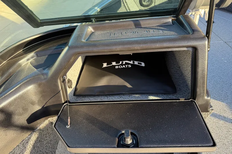 Slide: The Image of 2026 Lund 1875 Impact XS Sport boat storage compartment with Lund Boats logo. - 25