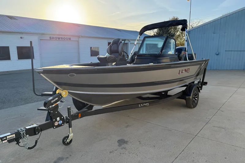 Slide: The Image of 2026 Lund 1875 Impact XS Sport boat on trailer, parked outside showroom at sunset. - 5