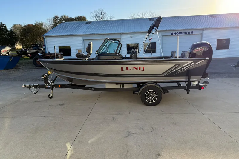 Slide: The Image of 2026 Lund 1875 Impact XS Sport boat on trailer outside showroom. - 7