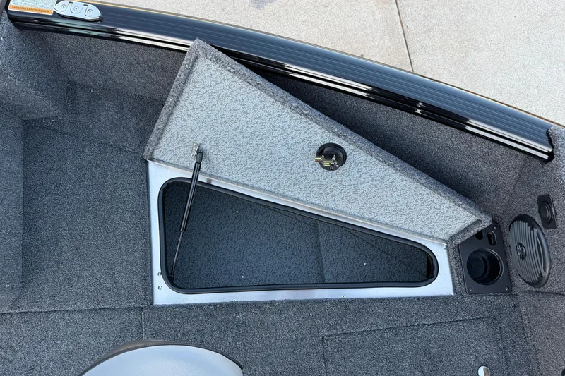 Slide: The Image of Open storage compartment on 2026 Lund 1775 Impact XS Sport boat, featuring carpeted interior. - 11