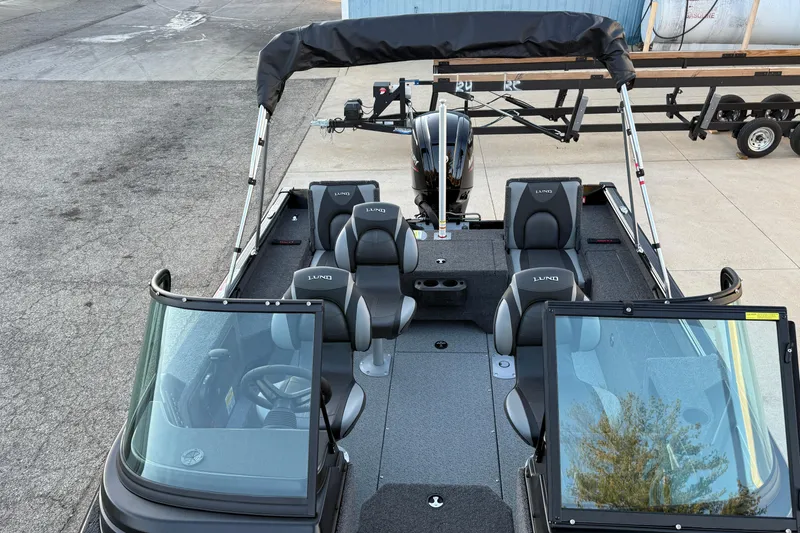 Slide: The Image of 2026 Lund 1775 Impact XS Sport boat with seating and windshield, parked on pavement. - 14