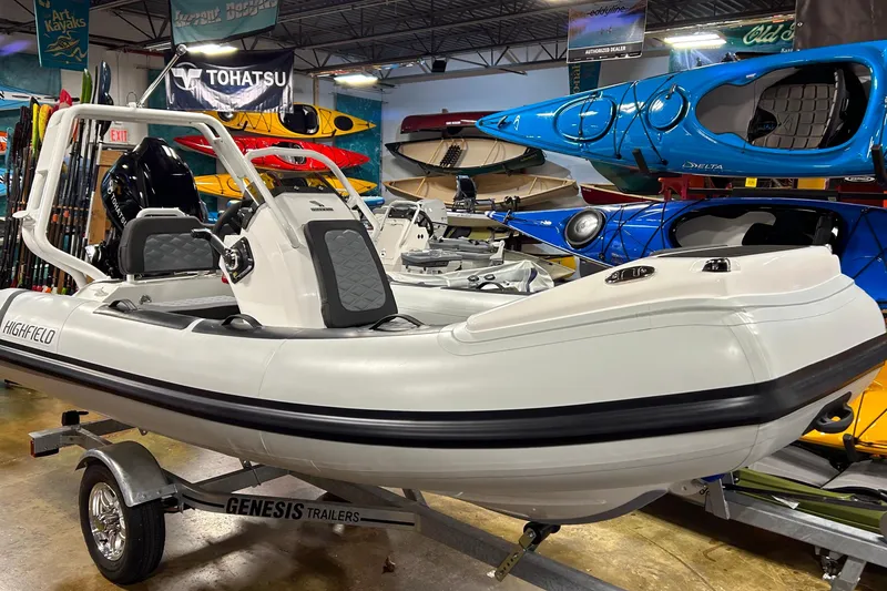 Slide: The Image of 2026 Highfield Sport 390 boat on Genesis trailer in showroom with kayaks. - 18