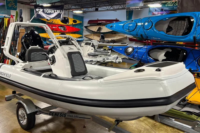 Slide: The Image of 2026 Highfield Sport 390 boat on trailer in showroom with kayaks displayed. - 19