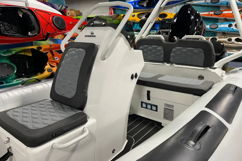 Slide: The Image of 2026 Highfield Sport 390 boat interior with gray seating, surrounded by colorful kayaks. - 9