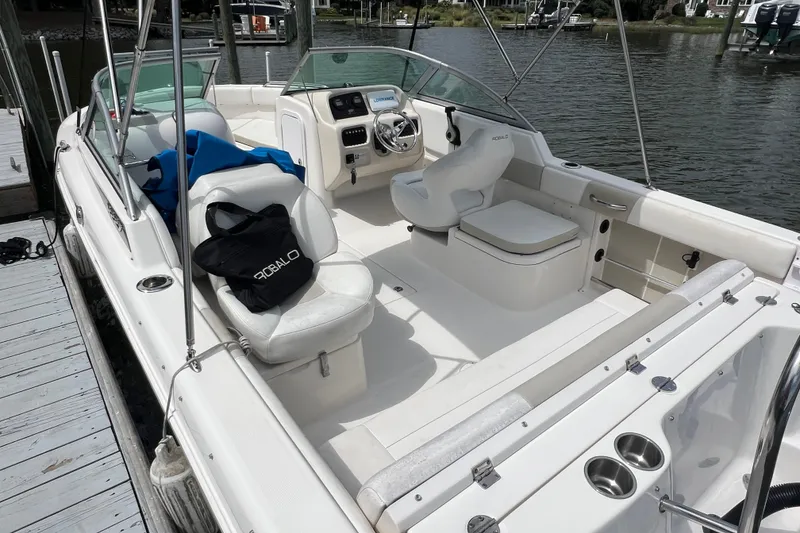 Slide: The Image of 2015 Robalo R227 Dual Console boat interior at dock, featuring seating and steering console. - 10