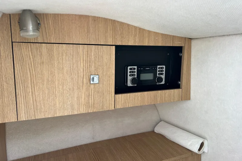 Slide: The Image of 2015 Robalo R227 Dual Console interior with wood paneling and built-in stereo system. - 16